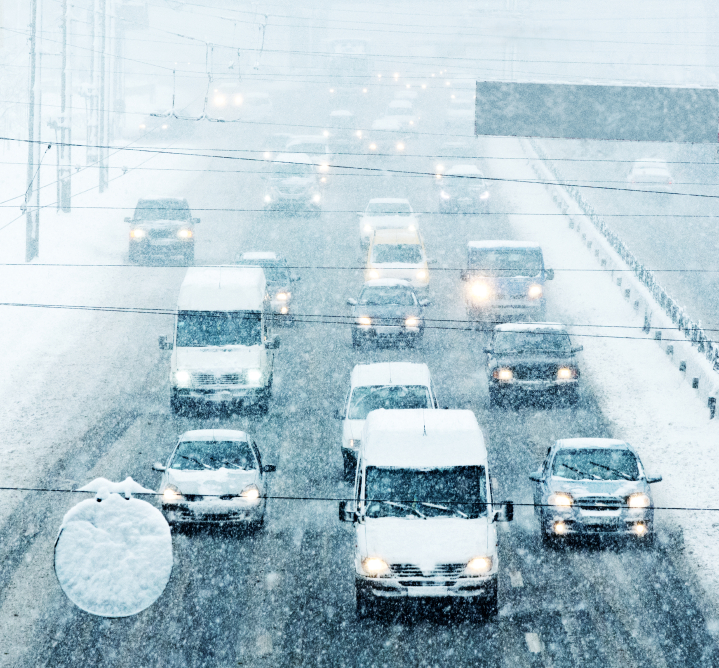 Snowy winter road with cars driving on roadway in snow storm